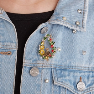 Detail of a sunflower and berry wreath brooch with rhinestones on denim jacket
