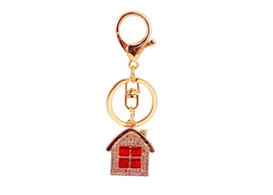 Detailed view of a golden house keychain with sparkling rhinestones and red gem windows