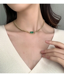 Close-up of asymmetrical 18K gold-plated necklace with a rectangular emerald pendant