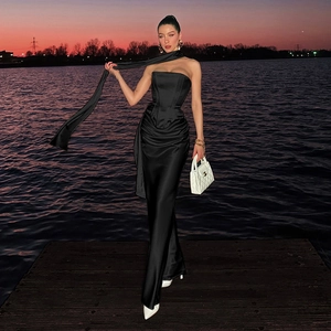 Elegante abito da sera in raso nero con sciarpa lunga al collo in riva al lago