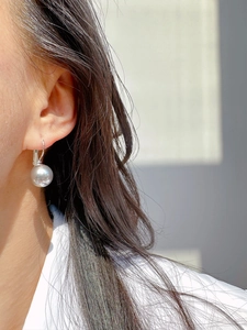 Macro detail of high-luster grey pearl on a classic silver leverback U-shaped earring