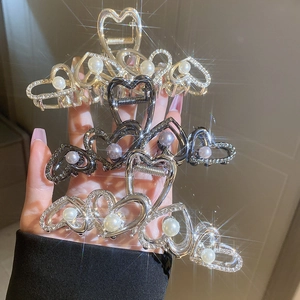 Détail de pinces à cheveux en métal en forme de cœur avec perles et strass en or, argent et noir