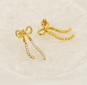 Macro detail of gold bow earrings featuring sparkling long tasseled zircon pendants