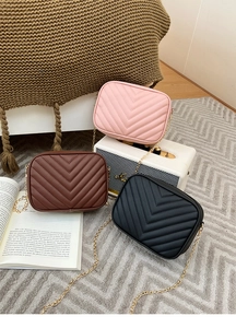 Detail view of quilted chain bags in pink, brown, and black with V-shaped embroidery
