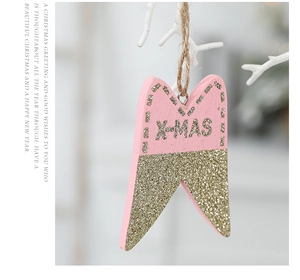 Close-up of pink wooden X-MAS star ornament with gold glitter hanging on jute twine