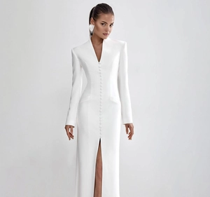 Detailed view of elegant white V-neck dress with fabric buttons and front slit
