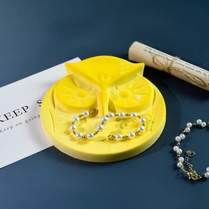 Détail macro du moule en silicone hibou jaune avec bracelets de perles sur fond bleu profond