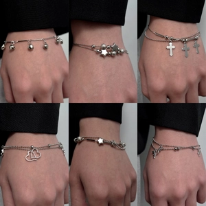 Silver stainless steel bracelet set with bell, star and cross charms on bead chains