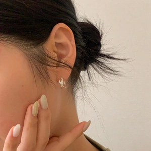 Close-up of minimalist 925 sterling silver twisted crossover stud earring on ear
