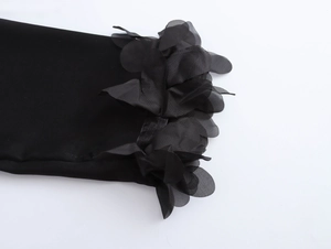 Close-up of elegant black sleeve cuff with 3D mesh floral applique on smooth fabric