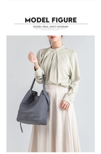 Gray woven PU leather tote bag styled on model with light green shirt and beige skirt
