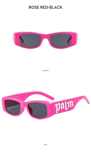 Detail of rose red thick frame sunglasses with black UV lenses and side silver lettering