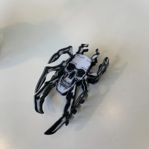Detailed view of Halloween hair claw clip featuring black spider and skull design on white surface