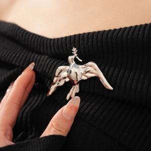Detail of silver liquid metal bird brooch with olive branch on black knitwear
