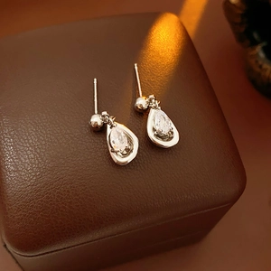 Macro view of sparkling teardrop zircon earrings on premium brown leather jewelry box