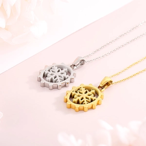 Detail of silver and gold snowflake gear necklaces on a soft pink petal background