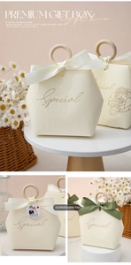 Detail of cream hexagonal wedding candy box with wooden handle and silk ribbon bow