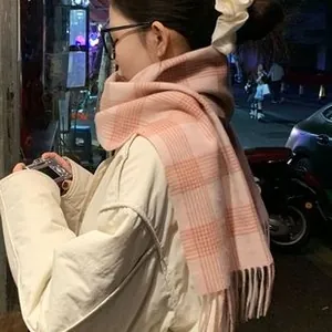Close-up of pink plaid scarf with tassels worn with a white scrunchie in street setting