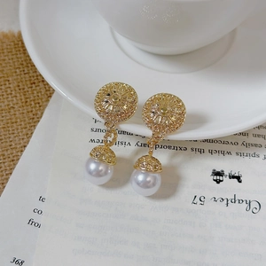 Detailed view of vintage pearl drop earrings with ornate gold floral engraving