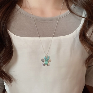 Detailed macro view of silver flower pendant necklace with turquoise stone on a model