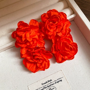 Detailed view of four handmade orange satin fabric rose flower jewelry accessories