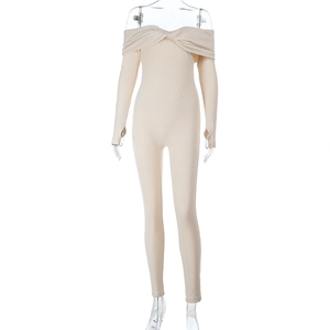 Dettaglio della trama in maglia della tuta beige con spalle scoperte a maniche lunghe