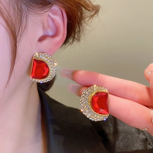 Vue détaillée de boucles d'oreilles vintage dorées avec pierre rouge et pavé de diamants brillants
