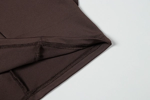 Close-up of deep brown knit fabric showing professional stitching and ruffled hem detail