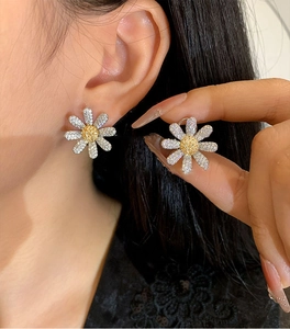Detail of daisy stud earrings with silver petals and yellow cubic zirconia stones