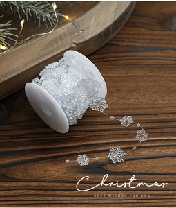 Transparent acrylic snowflake bead garland on spool with festive Christmas holiday decor