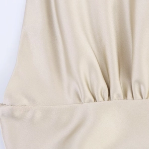Détail du tissu en satin champagne montrant les plis délicats et la texture soyeuse