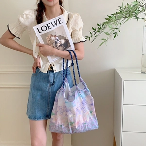 Detail of floral tote bag showing drawstring closure and blue rope handle texture