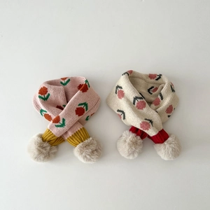 Detail of knit children scarves in pink and beige with cute floral prints and soft pom-poms