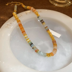 Détails de perles plates colorées et d'entretoises dorées sur un collier en acier inoxydable