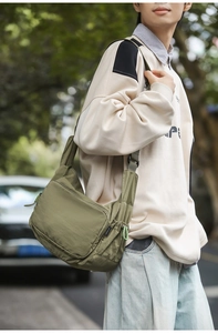 Outdoor street style shot of army green nylon messenger bag worn by a male model