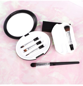 Detailed view of 5-piece makeup brush set with brown bristles and a mirrored travel case