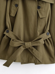 Detail of army green military jacket featuring waist tie bow and black resin buttons