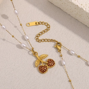 Detail of 18K gold plated necklace with cherry pendant and alternating pearls on a textured base