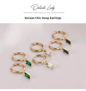 Detail of gold huggie hoop earrings with rectangular emerald, clear and black gemstones