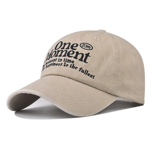 Detailed close-up of One Moment embroidery on washed khaki cotton baseball cap