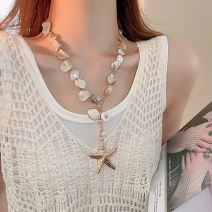 Close-up of beaded shell necklace featuring a golden starfish pendant on a model