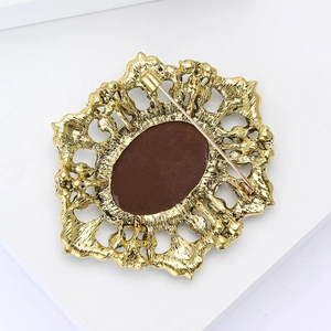 Close-up of vintage gold hollow brooch with brown gemstone inlay and rear clasp detail