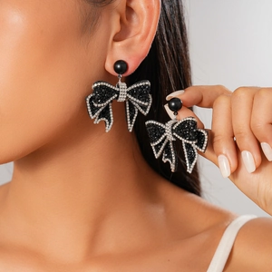 Gothic style bow earrings with black and silver rhinestones shown on a female model