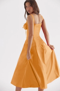 Detail view of bright orange sleeveless dress showing the elegant side-back draped cut