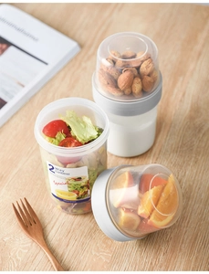Macro shot of double-layered portable food container with nuts and fresh fruit salad