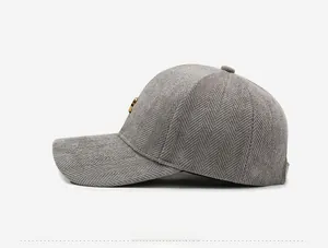 Detail of grey herringbone wool baseball cap featuring a round gold metal logo