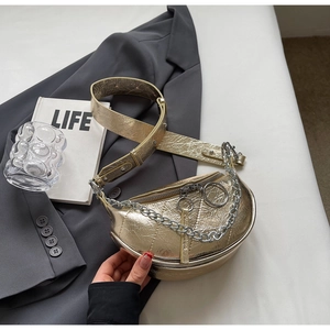 Detail of vintage saddle bag with gold metal finish and decorative silver chain strap