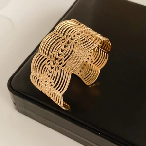 Détail du bracelet manchette ajouré doré avec des motifs géométriques gravés complexes