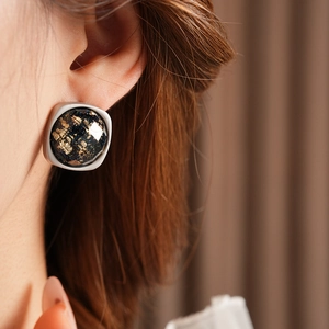 Gros plan de boucles d'oreilles carrées léopard avec bordure argentée sur un modèle