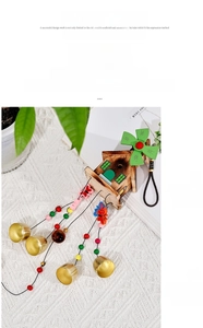 Close-up of wooden house wind chime with green blades, colorful beads and golden bells